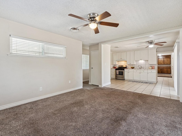 3672 N Shirley Ave, Fresno, CA 93727 - unfurnished living room featuring ceiling fan, light carpet, light tile patterned flooring, healthy amount of natural light, and a textured ceiling