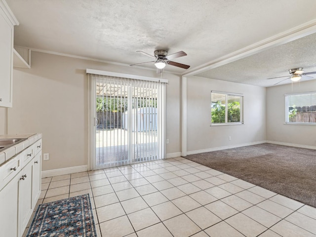 3672 N Shirley Ave, Fresno, CA 93727 - kitchen with a ceiling fan, a textured ceiling, white cabinetry, light countertops, and light colored carpet