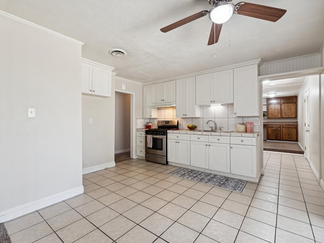 3672 N Shirley Ave, Fresno, CA 93727 - kitchen featuring gas stove, white cabinetry, tasteful backsplash, a ceiling fan, and under cabinet range hood