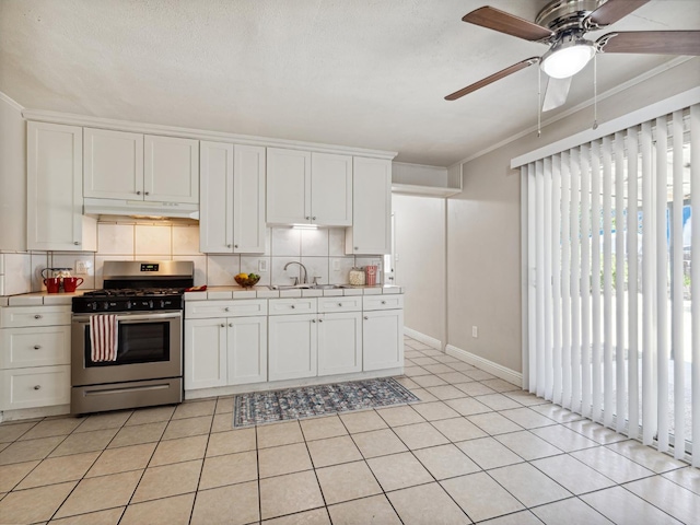 3672 N Shirley Ave, Fresno, CA 93727 - kitchen with stainless steel gas range, under cabinet range hood, tasteful backsplash, tile counters, and a ceiling fan