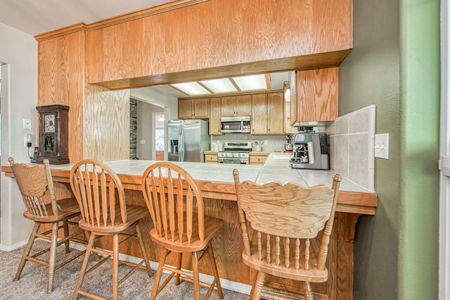 42052 Granite Ridge Rd, Shaver Lake, CA 93664 - kitchen with appliances with stainless steel finishes, tile countertops, a peninsula, a breakfast bar area, and backsplash