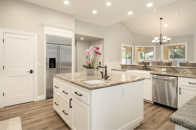 7671 N Ricewood Ave, Fresno, CA 93711 - kitchen with appliances with stainless steel finishes, a kitchen island with sink, white cabinetry, lofted ceiling, and light wood-style floors