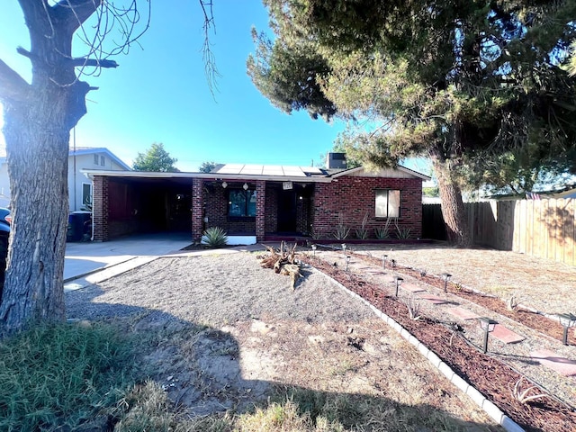 420 E Florinda St, Hanford, CA 93230 - view of front of property featuring roof mounted solar panels, brick siding, concrete driveway, and a carport