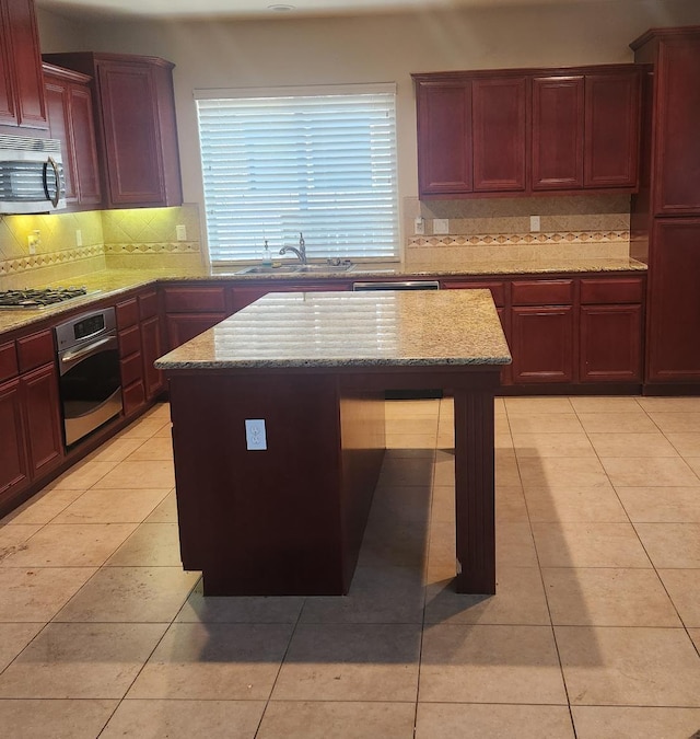 3310 N Jason Ave, Fresno, CA 93737 - kitchen with appliances with stainless steel finishes, reddish brown cabinets, decorative backsplash, and light stone countertops