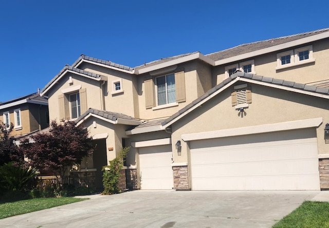 3310 N Jason Ave, Fresno, CA 93737 - view of front of house with stucco siding, stone siding, driveway, a tiled roof, and a garage