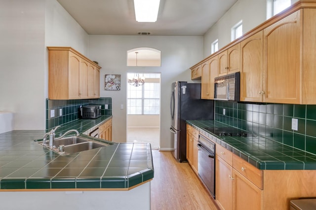 7515 N Wheeler Ave, Fresno, CA 93722 - kitchen featuring black appliances, a peninsula, a chandelier, backsplash, and light brown cabinets