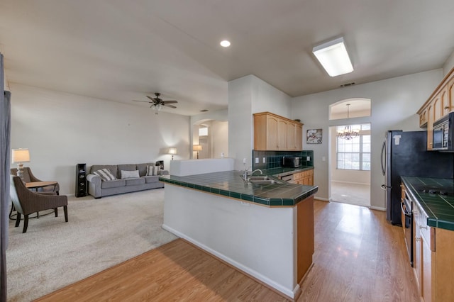 7515 N Wheeler Ave, Fresno, CA 93722 - kitchen featuring tile countertops, ceiling fan, light wood-style flooring, a chandelier, and a peninsula