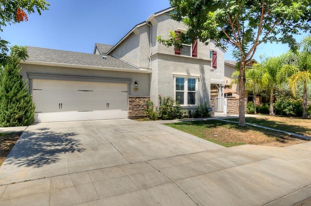 3669 N Clover Ave, Fresno, CA 93727 - view of front of home with stucco siding, concrete driveway, an attached garage, and stone siding