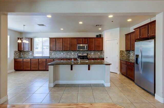 3669 N Clover Ave, Fresno, CA 93727 - kitchen with stainless steel appliances, backsplash, light tile patterned floors, dark stone counters, and a kitchen breakfast bar