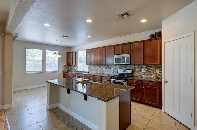 3669 N Clover Ave, Fresno, CA 93727 - kitchen with appliances with stainless steel finishes, decorative backsplash, light tile patterned floors, dark stone counters, and recessed lighting