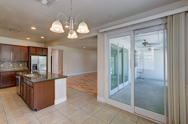3669 N Clover Ave, Fresno, CA 93727 - kitchen featuring stainless steel appliances, light tile patterned flooring, decorative backsplash, dark stone counters, and pendant lighting