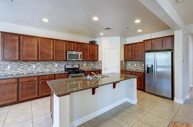 3669 N Clover Ave, Fresno, CA 93727 - kitchen with appliances with stainless steel finishes, dark stone countertops, decorative backsplash, an island with sink, and recessed lighting