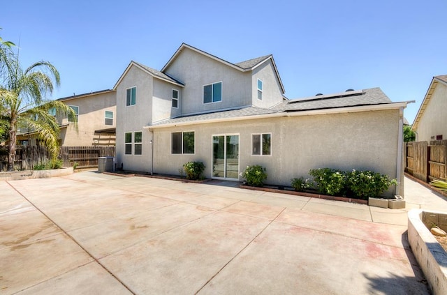 3669 N Clover Ave, Fresno, CA 93727 - back of property featuring stucco siding, roof mounted solar panels, a fenced backyard, a patio, and roof with shingles