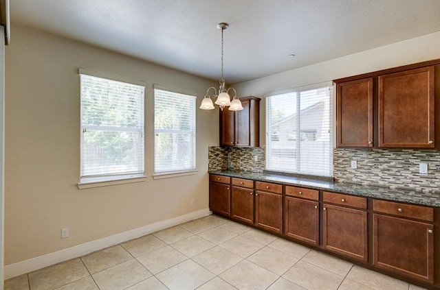 3669 N Clover Ave, Fresno, CA 93727 - kitchen with decorative backsplash, a chandelier, light tile patterned floors, pendant lighting, and dark stone counters