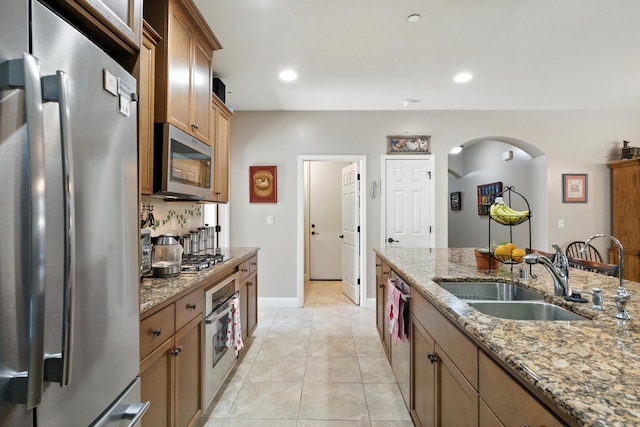 5822 E Booker Ave, Fresno, CA 93727 - kitchen with stainless steel appliances, arched walkways, light stone counters, light tile patterned flooring, and recessed lighting