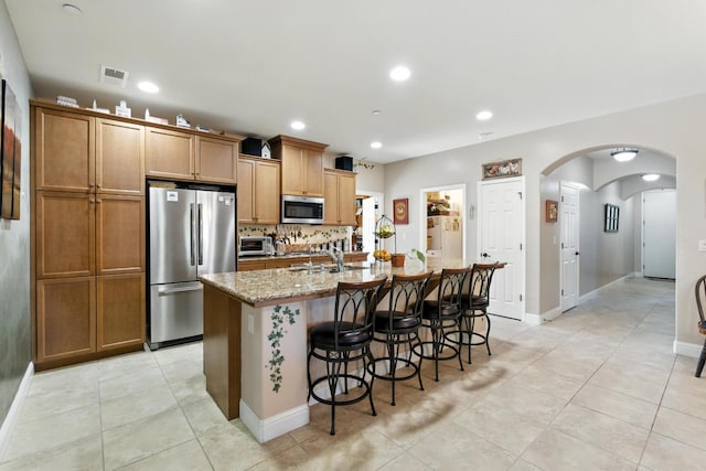 5822 E Booker Ave, Fresno, CA 93727 - kitchen with stainless steel appliances, a kitchen island with sink, a kitchen bar, light tile patterned floors, and recessed lighting