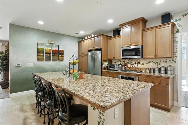 5822 E Booker Ave, Fresno, CA 93727 - kitchen with appliances with stainless steel finishes, light stone countertops, an island with sink, recessed lighting, and a breakfast bar