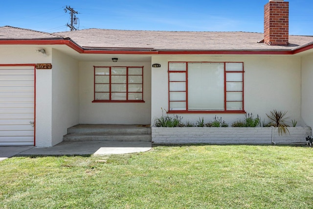 3677 N Thesta St, Fresno, CA 93726 - property entrance with a chimney, stucco siding, a lawn, and roof with shingles