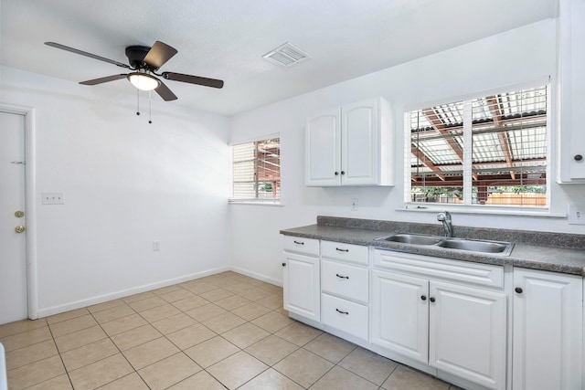 3677 N Thesta St, Fresno, CA 93726 - kitchen with dark countertops, ceiling fan, white cabinetry, and light tile patterned floors