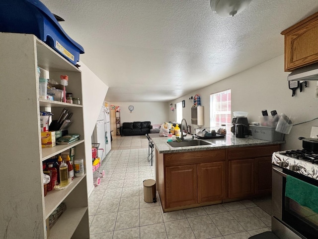 1925 E 15th, Oakland, CA 94606 - kitchen featuring stainless steel range with gas cooktop, open floor plan, light tile patterned flooring, a peninsula, and a textured ceiling