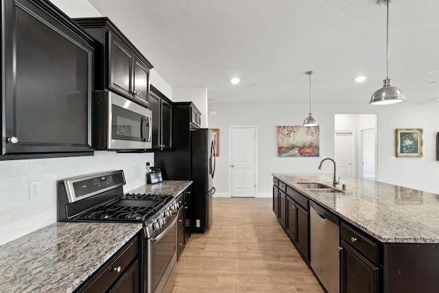2456 Junipero Ave, Clovis, CA 93619 - kitchen featuring stainless steel appliances, light wood finished floors, decorative backsplash, light stone countertops, and a kitchen island with sink