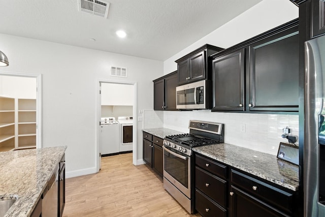 2456 Junipero Ave, Clovis, CA 93619 - kitchen with appliances with stainless steel finishes, separate washer and dryer, light wood-style flooring, tasteful backsplash, and light stone counters
