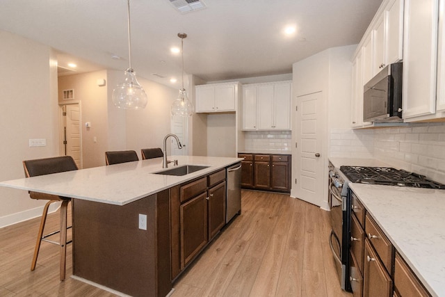 153 N Bliss Ave, Fresno, CA 93727 - kitchen featuring stainless steel appliances, light wood-style floors, white cabinetry, a breakfast bar, and recessed lighting