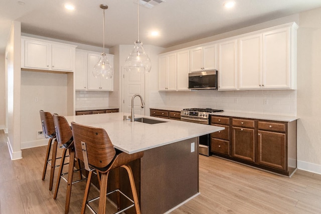153 N Bliss Ave, Fresno, CA 93727 - kitchen featuring stainless steel appliances, white cabinets, decorative backsplash, a kitchen island with sink, and recessed lighting