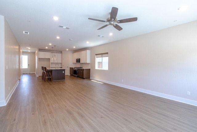 153 N Bliss Ave, Fresno, CA 93727 - unfurnished living room with light wood finished floors, healthy amount of natural light, a ceiling fan, and recessed lighting