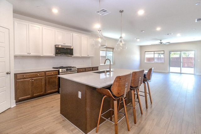 153 N Bliss Ave, Fresno, CA 93727 - kitchen featuring stainless steel appliances, decorative backsplash, light wood-type flooring, a center island with sink, and a breakfast bar area