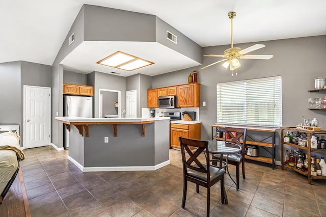 205 N Douglas Ave, Fresno, CA 93727 - kitchen featuring appliances with stainless steel finishes, light countertops, ceiling fan, a kitchen island with sink, and a breakfast bar