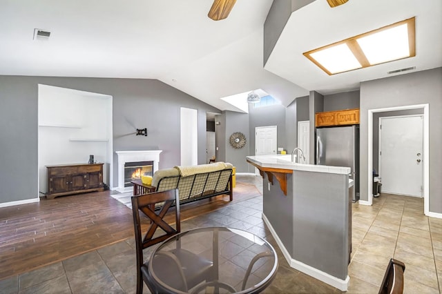205 N Douglas Ave, Fresno, CA 93727 - kitchen with tile countertops, lofted ceiling, freestanding refrigerator, a glass covered fireplace, and brown cabinetry