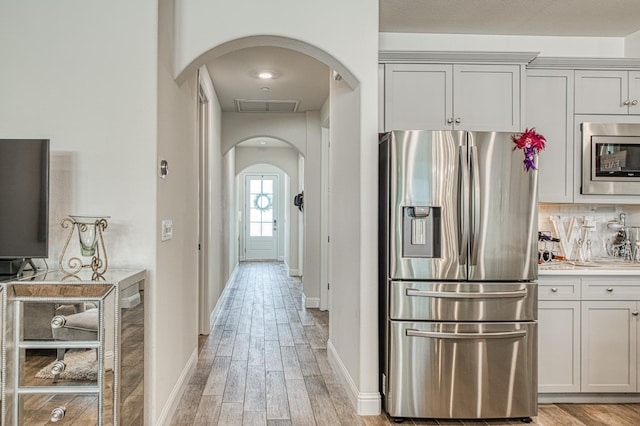 1363 E Via Prato Dr, Fresno, CA 93730 - kitchen with stainless steel appliances, arched walkways, light wood-type flooring, light countertops, and decorative backsplash