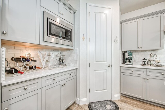 1363 E Via Prato Dr, Fresno, CA 93730 - kitchen with stainless steel microwave, decorative backsplash, light countertops, and gray cabinets