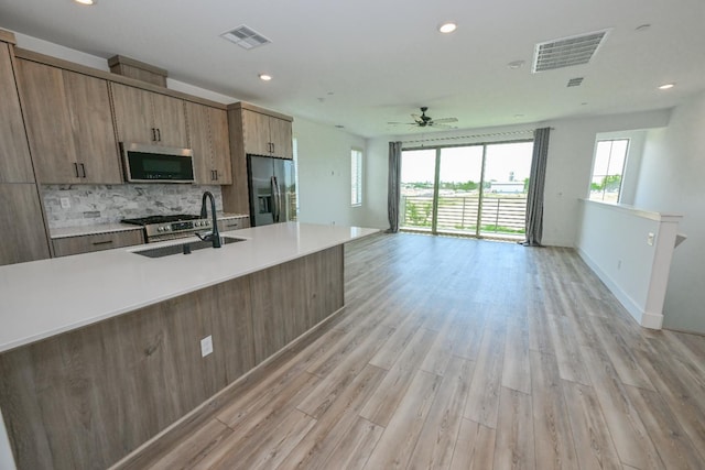 510 W Mahogany Ln, Clovis, CA 93611 - kitchen featuring stainless steel appliances, open floor plan, tasteful backsplash, light countertops, and light wood-style flooring