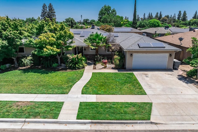 6052 N Spalding Ave, Fresno, CA 93710 - view of front of house featuring a front yard, driveway, stucco siding, a garage, and roof mounted solar panels