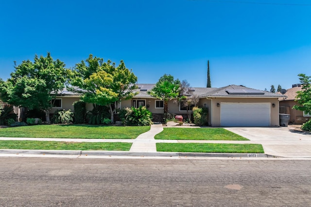 6052 N Spalding Ave, Fresno, CA 93710 - ranch-style house with stucco siding, a front lawn, a garage, solar panels, and driveway