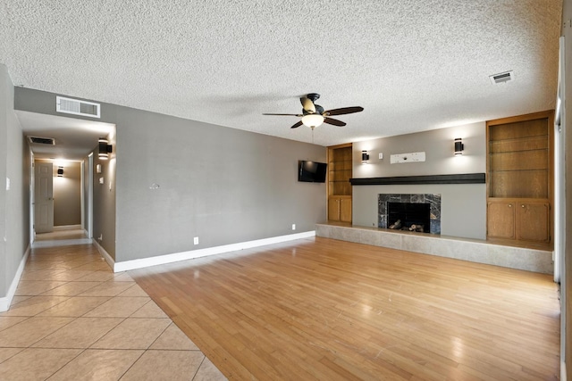6052 N Spalding Ave, Fresno, CA 93710 - unfurnished living room featuring a ceiling fan, a high end fireplace, a textured ceiling, and light wood-style flooring