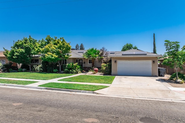 6052 N Spalding Ave, Fresno, CA 93710 - ranch-style house with stucco siding, concrete driveway, an attached garage, and roof mounted solar panels
