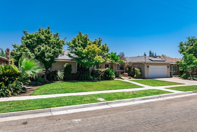 6052 N Spalding Ave, Fresno, CA 93710 - view of front facade featuring stucco siding, an attached garage, driveway, roof mounted solar panels, and a front yard