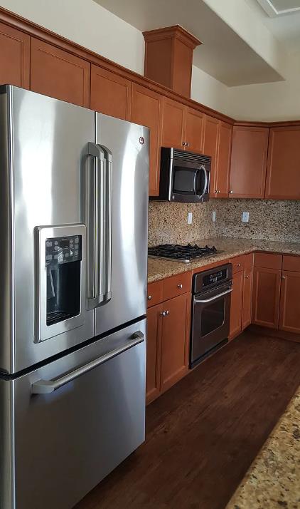 1982 N Todd Hedrick, Clovis, CA 93619 - kitchen with stainless steel appliances, dark wood-style floors, brown cabinetry, light stone countertops, and decorative backsplash