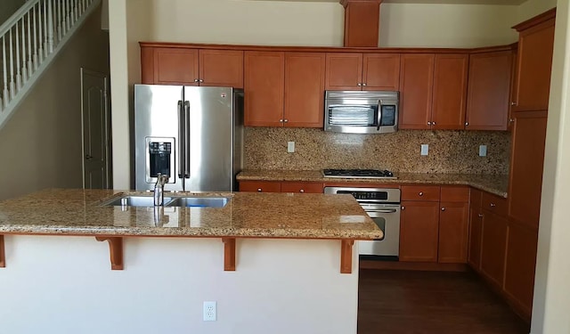 1982 N Todd Hedrick, Clovis, CA 93619 - kitchen featuring appliances with stainless steel finishes, dark wood-type flooring, tasteful backsplash, a breakfast bar area, and light stone counters