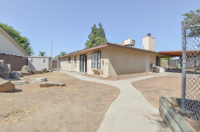1325 Griffith Ave, Clovis, CA 93612 - rear view of property featuring a storage unit, stucco siding, and a chimney