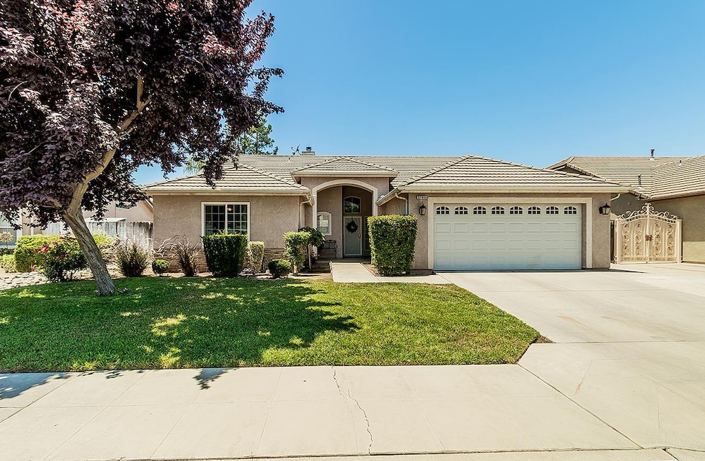 5783 N State St, Fresno, CA 93722 - ranch-style home featuring stucco siding, an attached garage, a tile roof, driveway, and a front yard