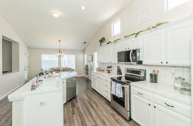 5783 N State St, Fresno, CA 93722 - kitchen with stainless steel appliances, tile countertops, lofted ceiling, healthy amount of natural light, and recessed lighting