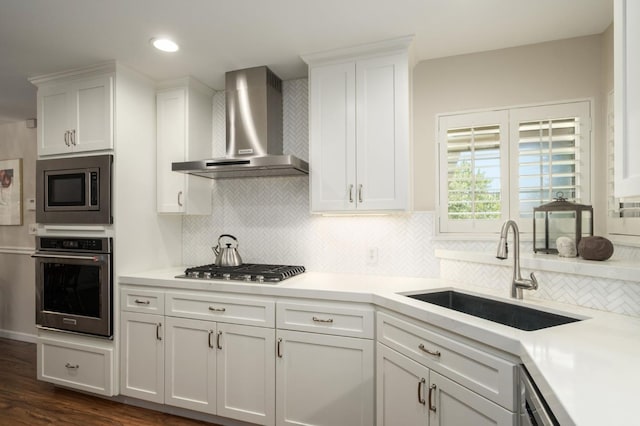 3218 E Ellery Ave, Fresno, CA 93710 - kitchen featuring appliances with stainless steel finishes, wall chimney range hood, white cabinets, decorative backsplash, and recessed lighting