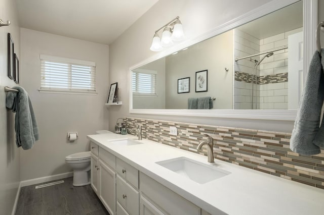 3218 E Ellery Ave, Fresno, CA 93710 - bathroom with double vanity, decorative backsplash, a tile shower, and wood finished floors