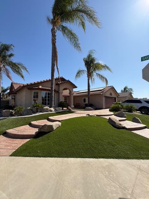 513 Chianti Ct, Madera, CA 93637 - mediterranean / spanish-style home with driveway, a tile roof, a front lawn, and stucco siding