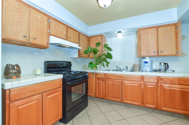 4879 E San Gabriel Ave, Fresno, CA 93726 - kitchen featuring gas stove, under cabinet range hood, backsplash, and light tile patterned flooring