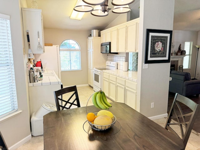 650 N Burgan Ave, Fresno, CA 93727 - dining space featuring light tile patterned floors, a chandelier, lofted ceiling, and a fireplace